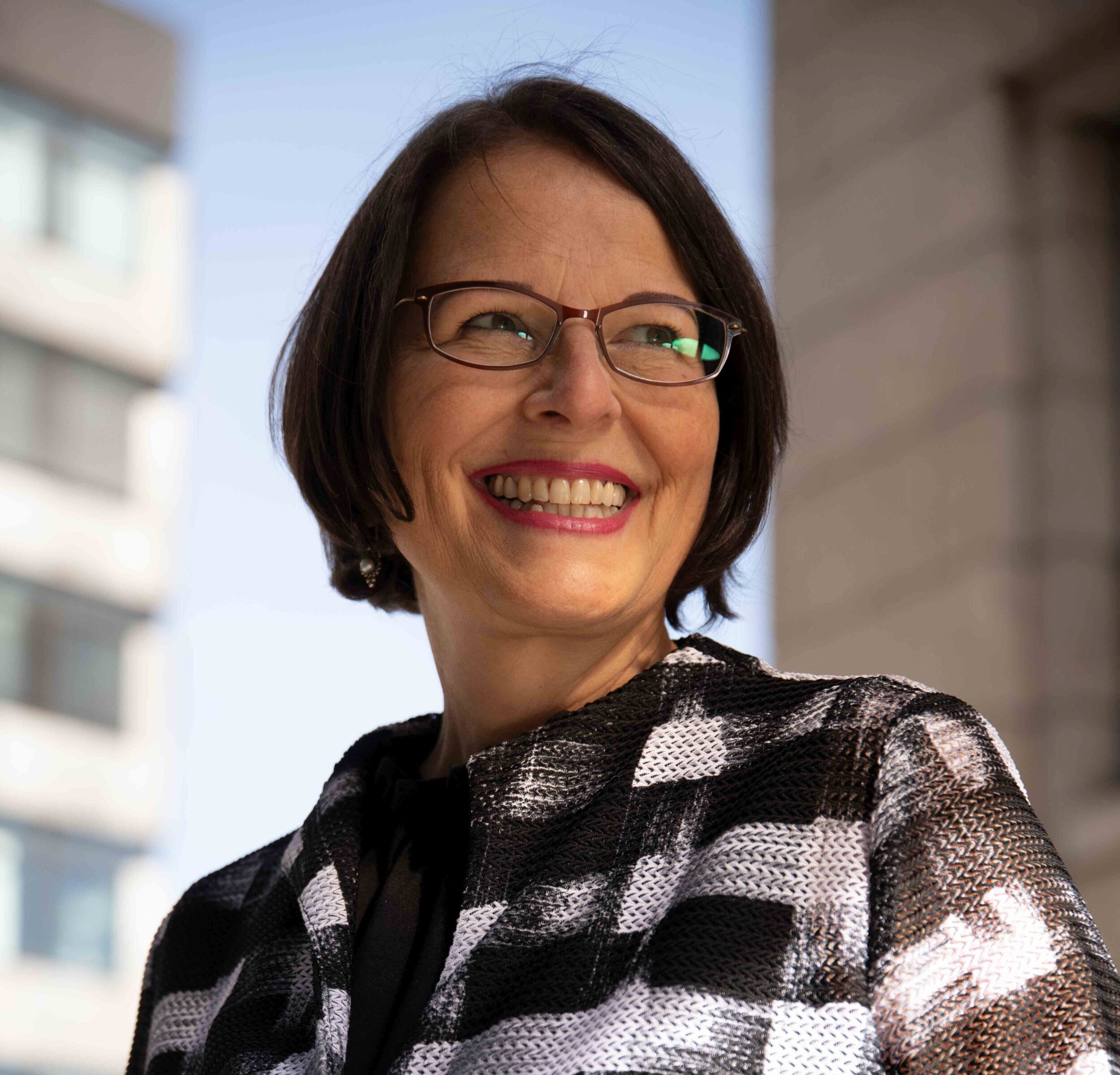 Zu sehen ist ein Portrait der Intendantin CHristine Fischer. Sie trägt ein schwarz-weiß gemustertes Oberteil.