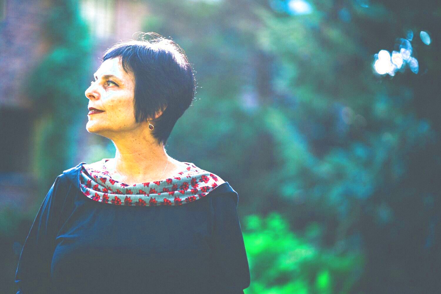 Das Porträt einer Frau (Chaya Czernowin). Sie trägt ein schwarzes Oberteil und blickt weg. Der Hintergrund ist grün und verschwommen.